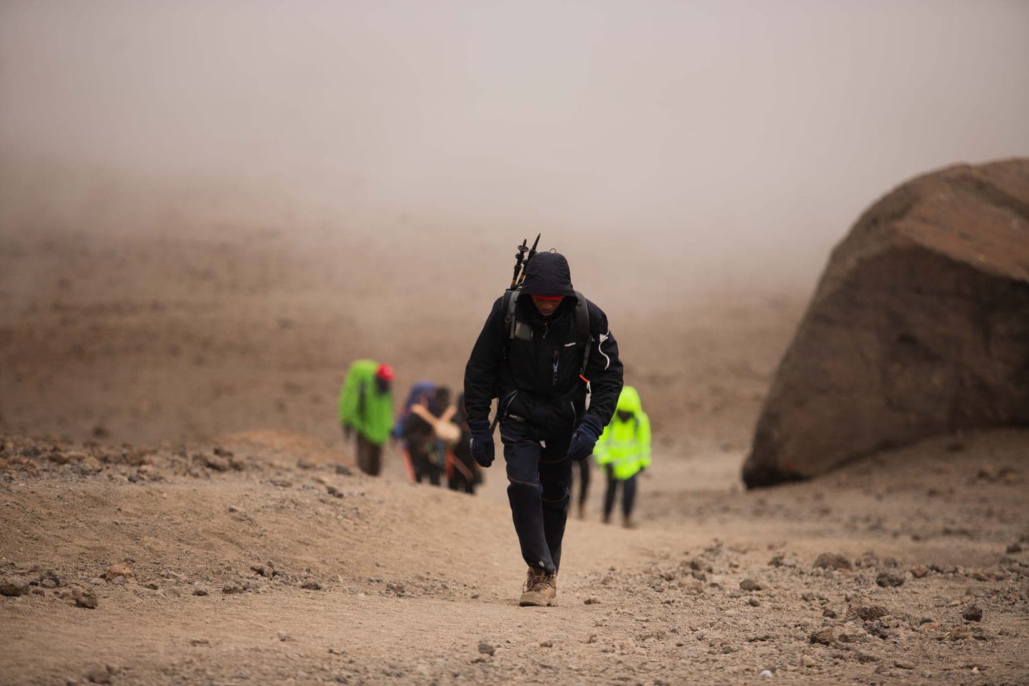 Hikers climbing a dusty slope in the fog