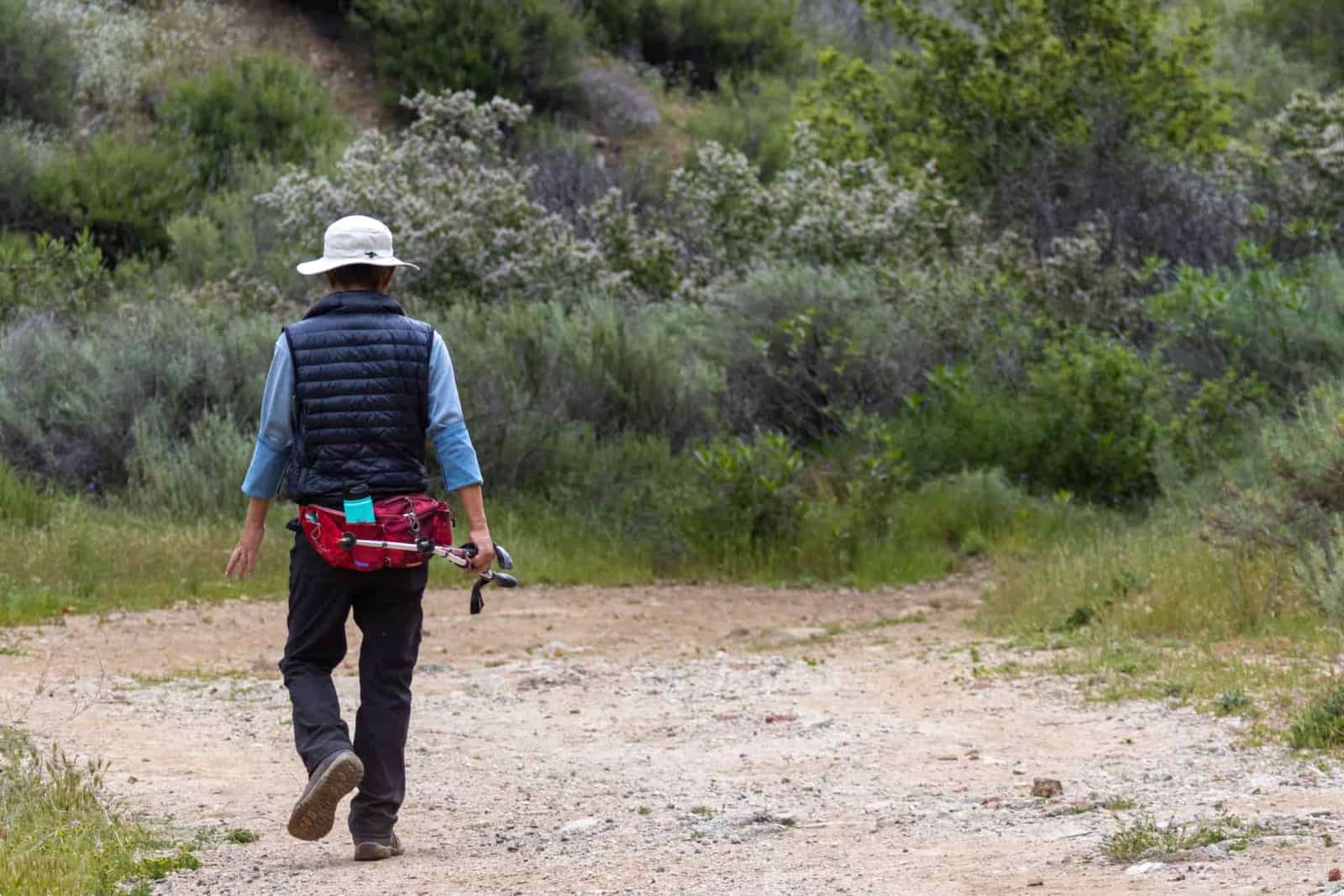 A hiker in a sun hat walking a country trail