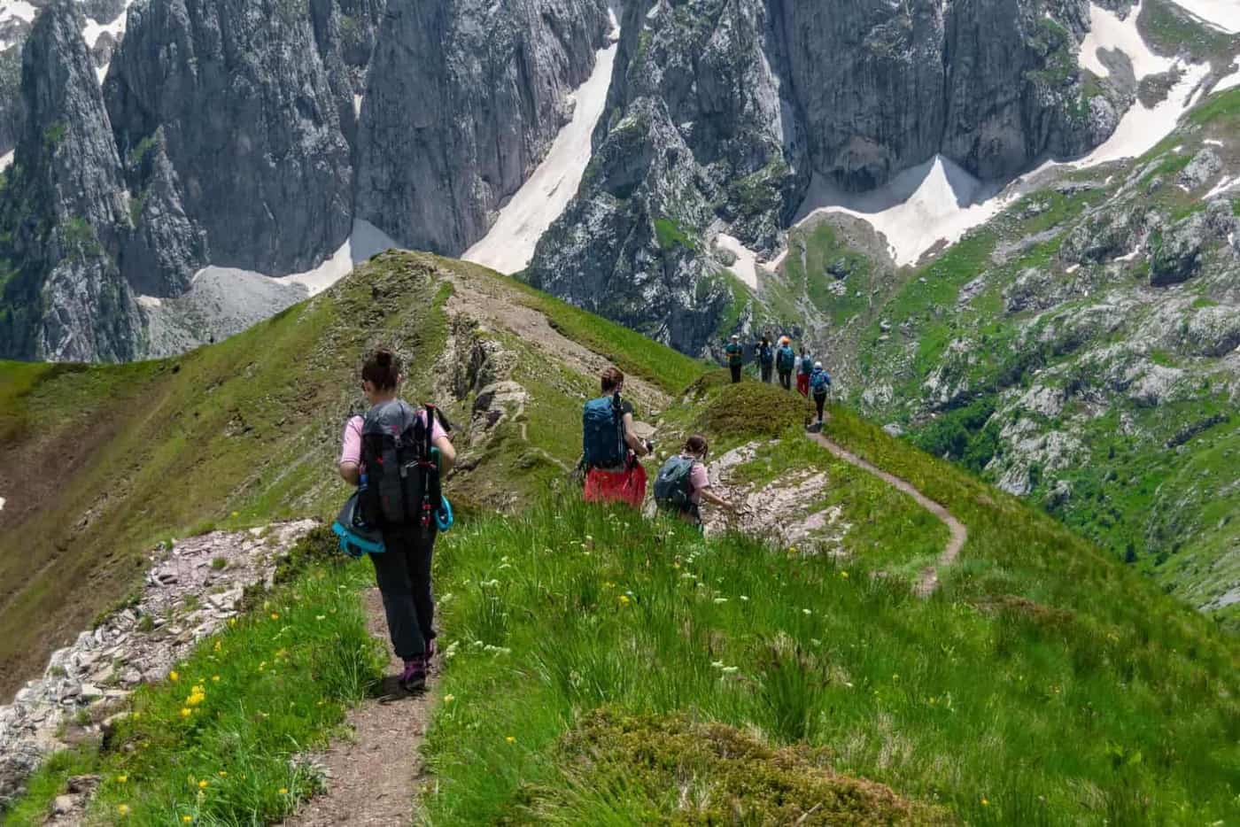 Hikers walking a grassy mountain ridge trail