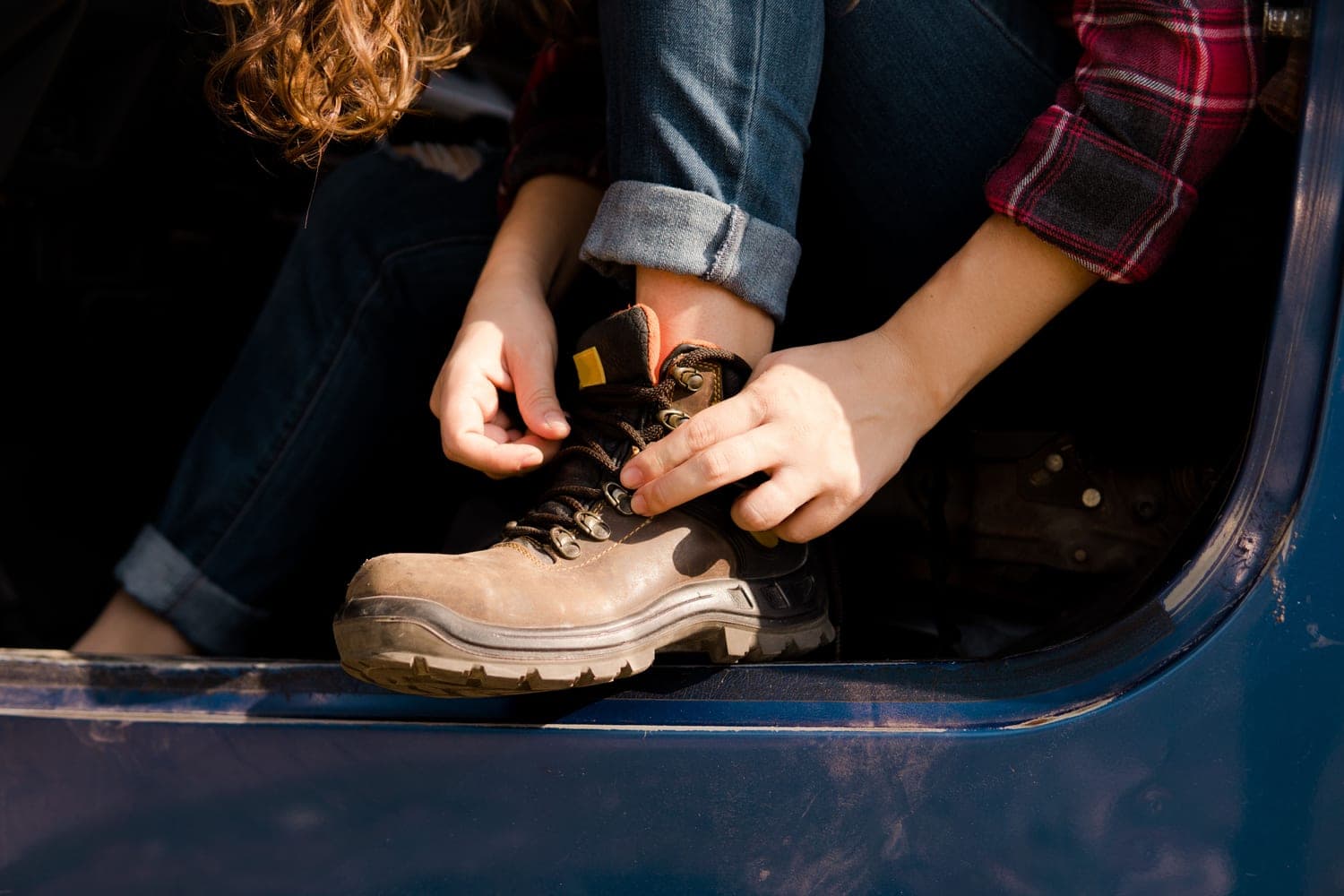 A person tying the laces of a leather hiking boot