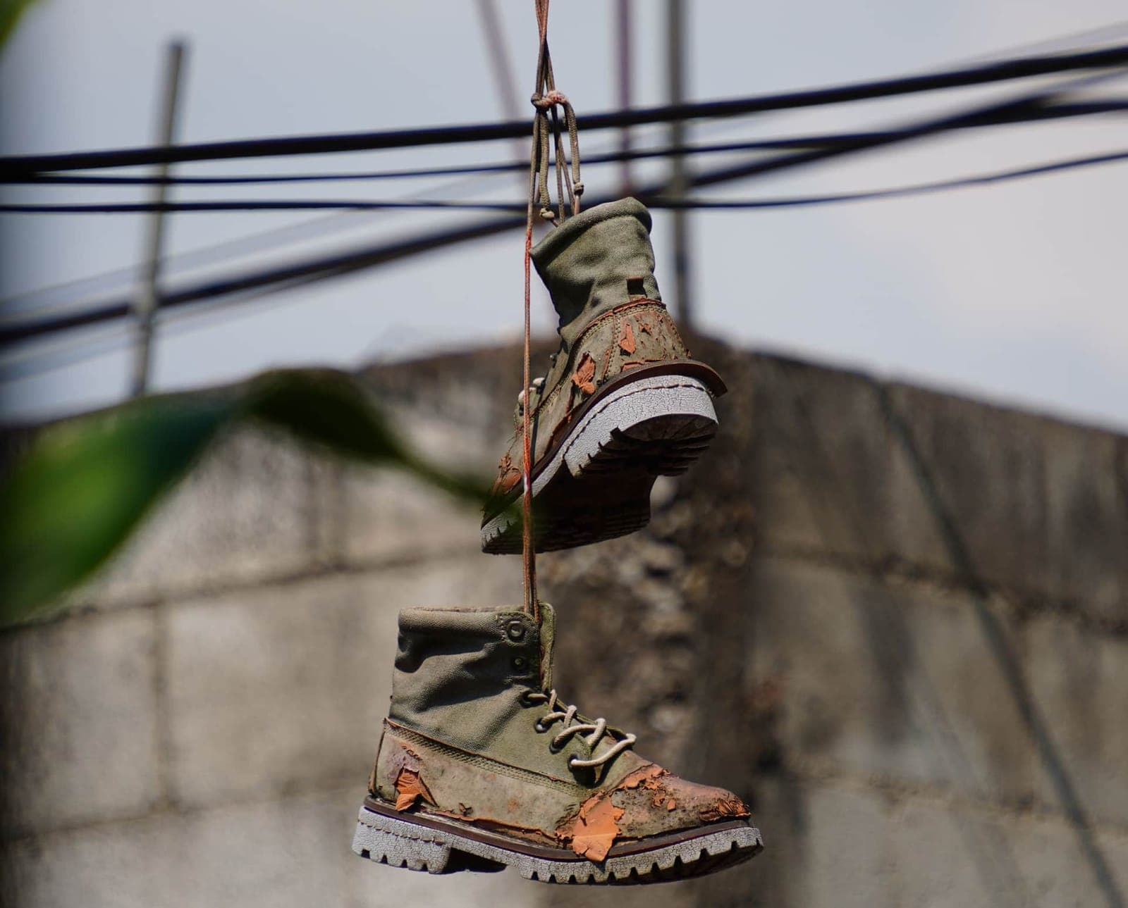 A pair of worn-out boots hanging from a wire