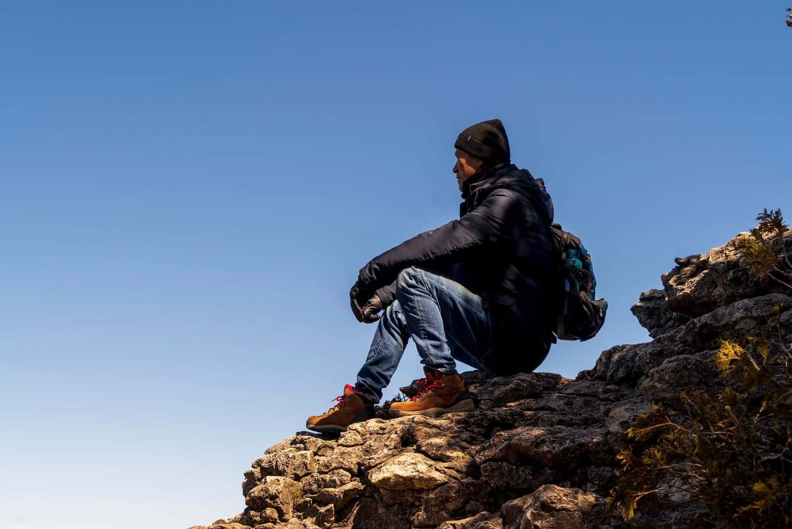 A hiker sitting on a rocky outcrop under a blue sky