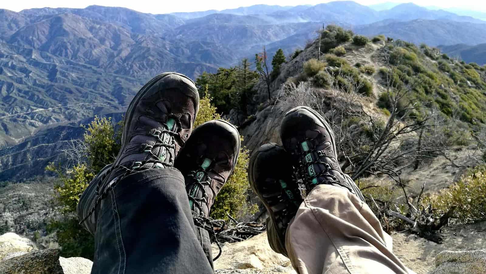 Two hikers resting with their boots up, overlooking mountain ridges